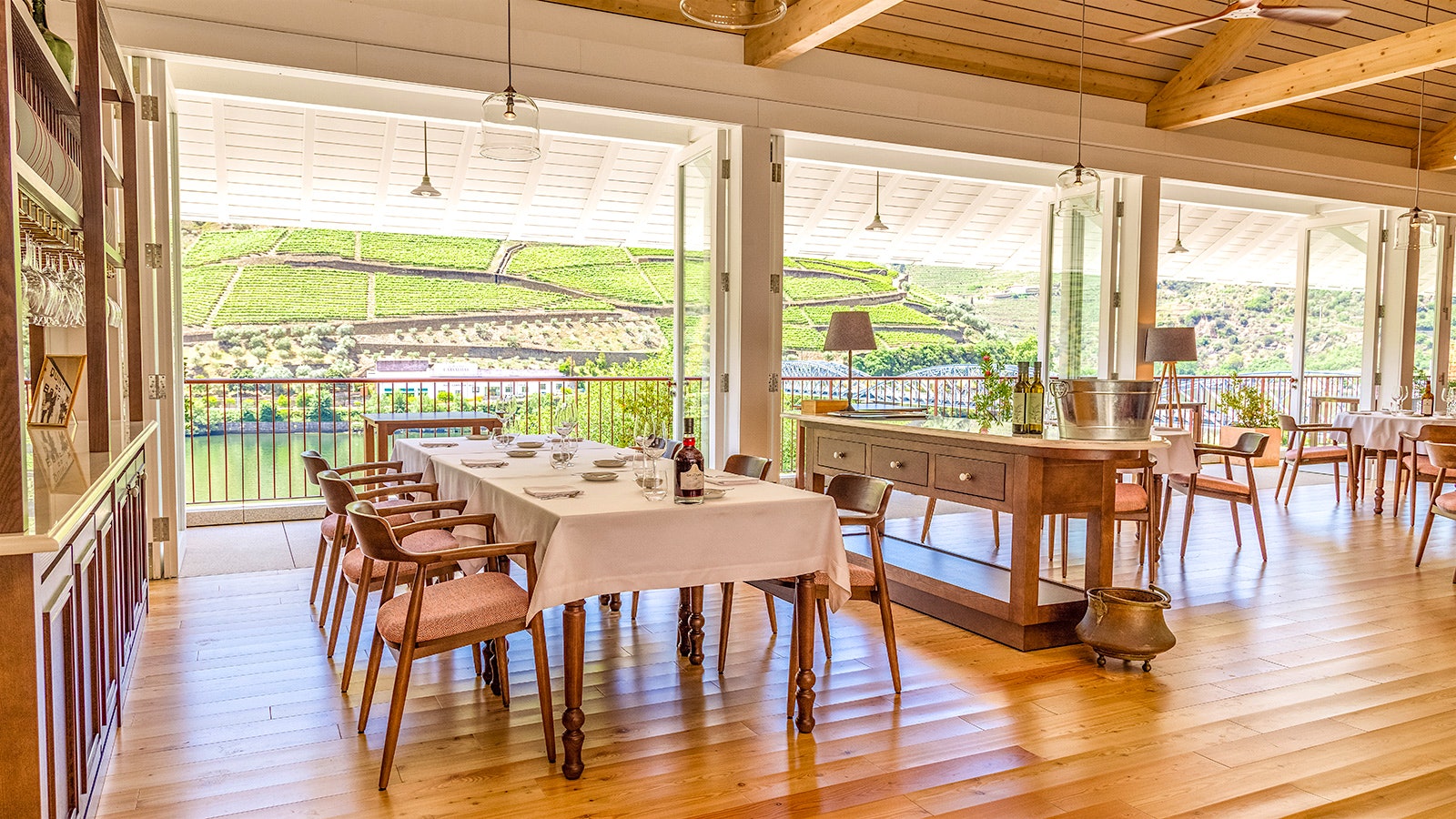 The light-wood interior of Bomfim 1896 restaurant with views out the floor-to-ceiling windows of Douro vineyards